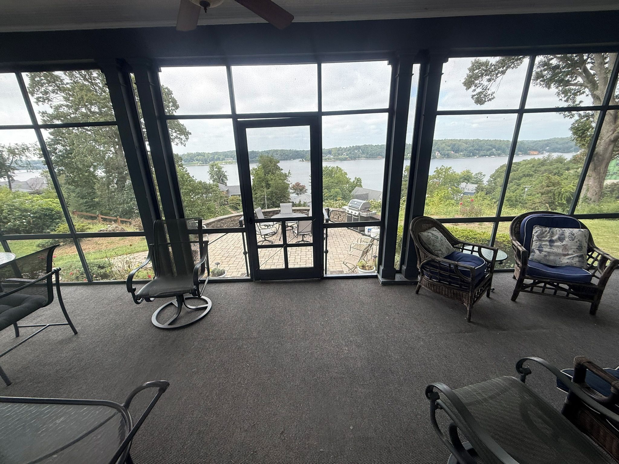 A room with large windows overlooking a body of water, furnished with chairs and a table.