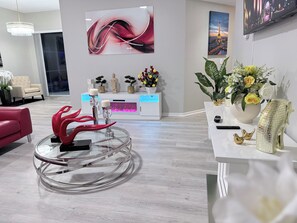 A modern interior with a glass coffee table, a white reception desk, and a wall-mounted TV. - Tremendous 4-bedroom house with AC in charming Kissimmee (Kissimmee)