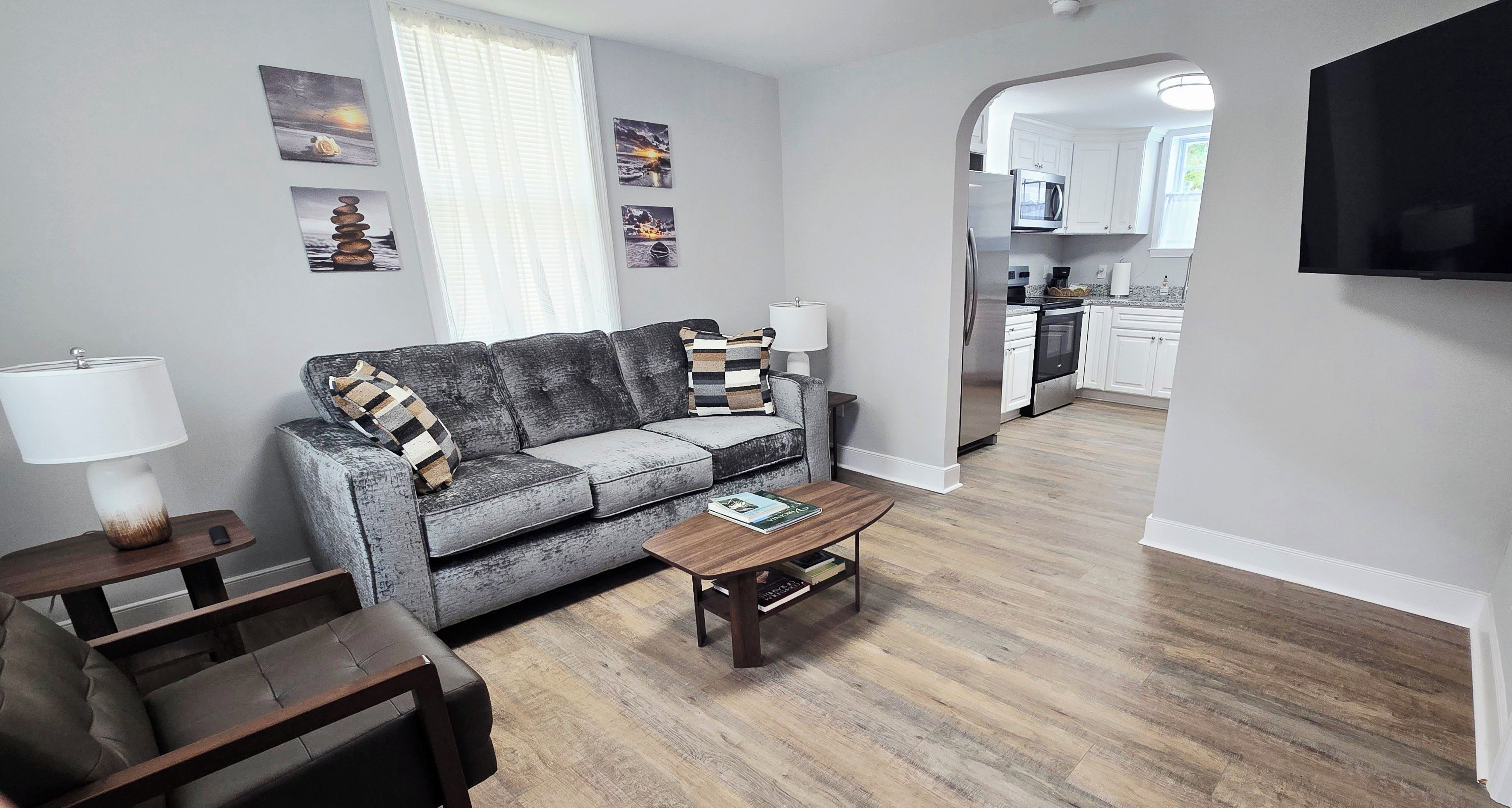 A living room with a sofa, coffee table, and a TV mounted on the wall.