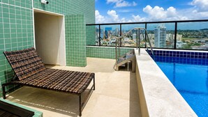 A rooftop pool area with a lounge chair, a small staircase, and a city view. - Premium Apartment in Olinda | Swimming Pool, Gym, and Panoramic Ocean Views (Recife)