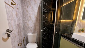 A compact bathroom with a toilet, a shower enclosure, and a sink. - Premium Apartment in Olinda | Swimming Pool, Gym, and Panoramic Ocean Views (Recife)