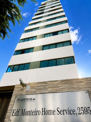 Een hoog gebouw met een bord waarop 'Gerisa Empreendimentos' en 'Edf. Monteiro Home Service, 2595' staat.