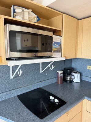 Eine kompakte Küchenzeile mit einer eingebauten Mikrowelle, einer Kaffeemaschine und einem Toaster auf einer Arbeitsplatte aus Granit.