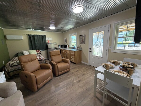 A compact living space with a kitchenette, a dining area, and a seating area with two leather chairs.