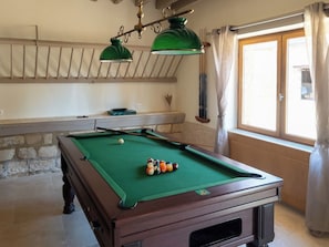 Una mesa de billar con bolas, superficie de fieltro verde y estructura de madera.
