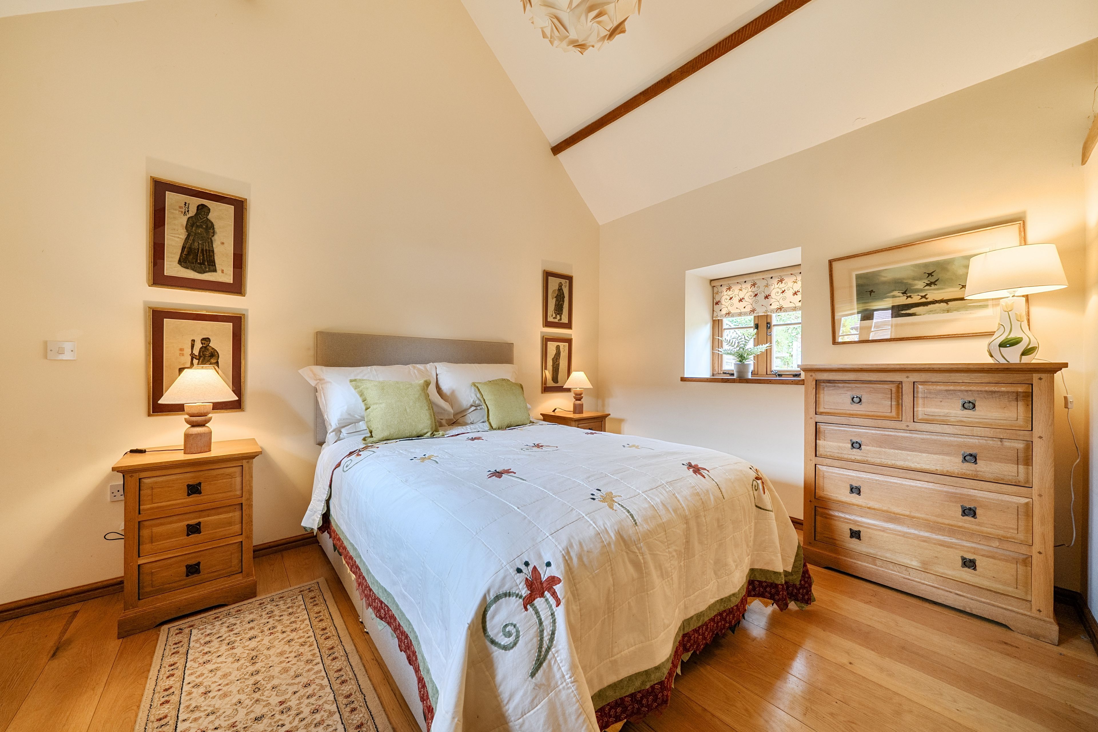 A bedroom with a bed, bedside tables, a dresser, and wall-mounted lamps.