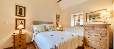 A bedroom with a bed, bedside tables, a dresser, and wall-mounted lamps.