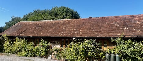 Un bâtiment en bois doté d’un toit en pente, entouré d’une végétation luxuriante et accessible par une allée de gravier.