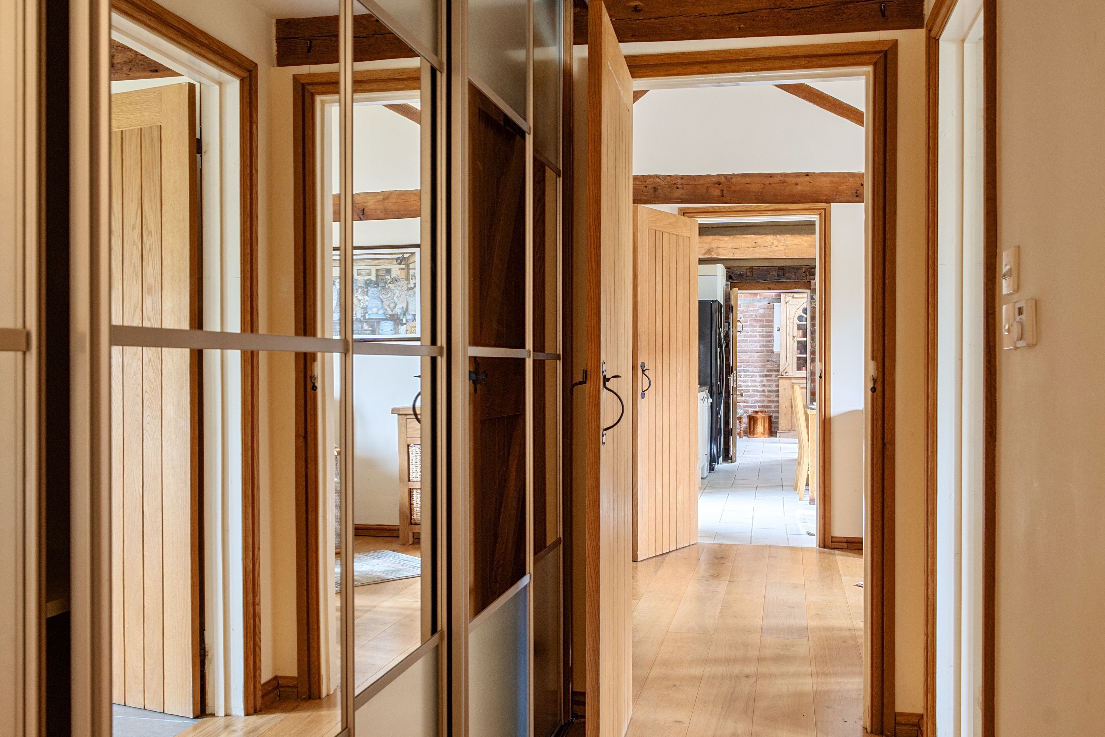 Un couloir avec des portes en bois et une vue sur une autre pièce.
