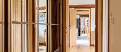 A hallway with wooden doors and a view into another room.