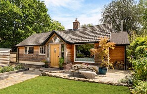 A small, single-story house with a stone facade, a wooden door, and a small porch area.