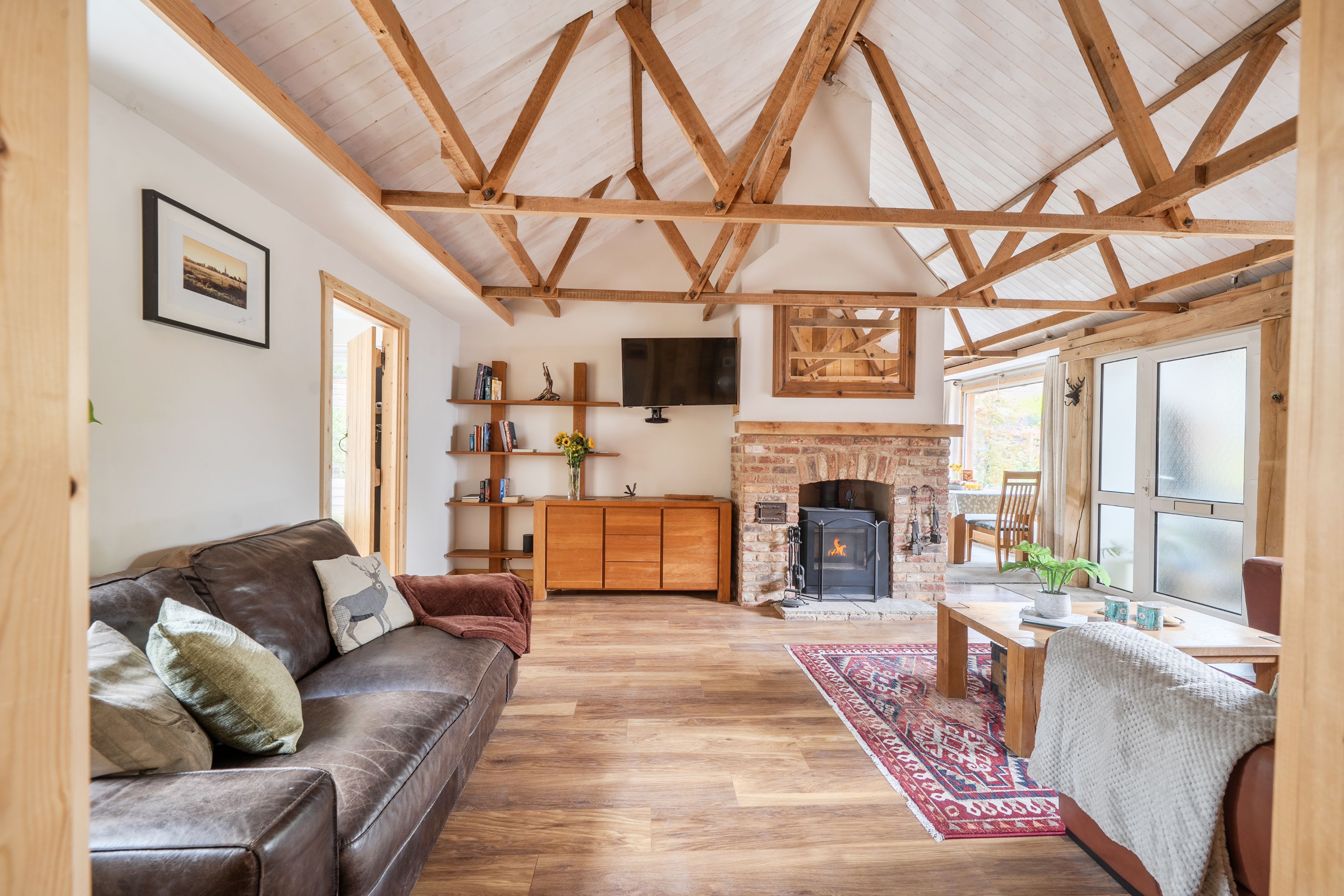 A spacious living room with a wooden ceiling, a fireplace, a sofa, and a television.