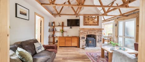A spacious living room with a wooden ceiling, a fireplace, a sofa, and a television.