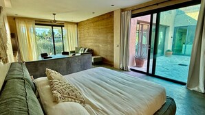 Quarto moderno com uma cama grande, um sofá, uma escrivaninha e vista para o exterior.