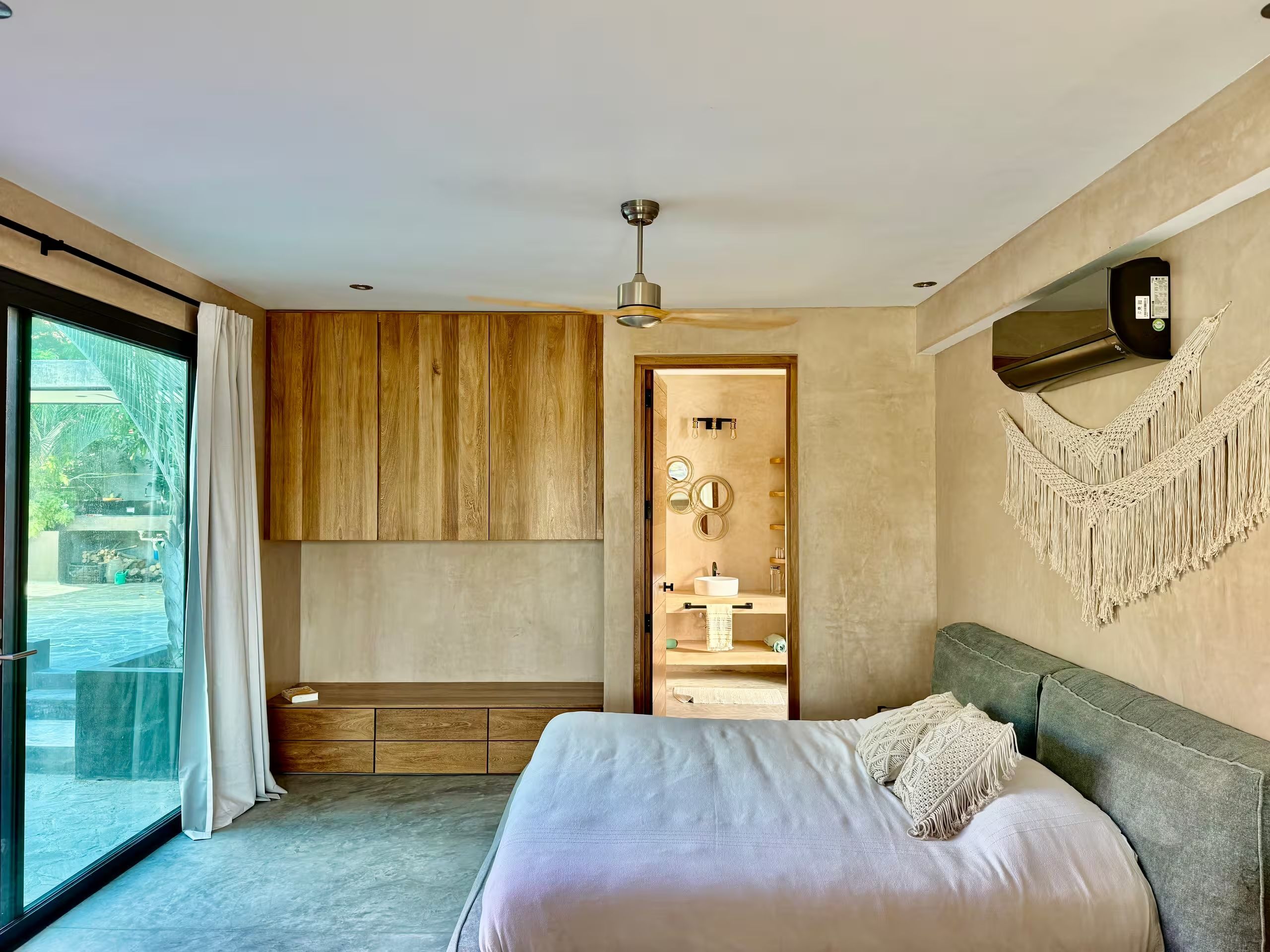 A modern bedroom with a large bed, a ceiling fan, and a view of a swimming pool.