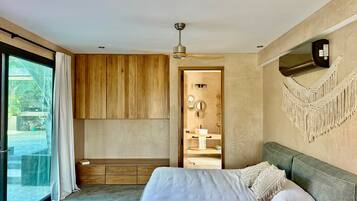 A modern bedroom with a large bed, a ceiling fan, and a view of a swimming pool.