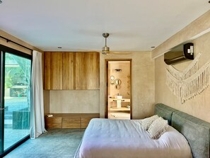 Ein modernes Schlafzimmer mit einem großen Bett, einem Deckenventilator und Blick auf einen Swimmingpool.