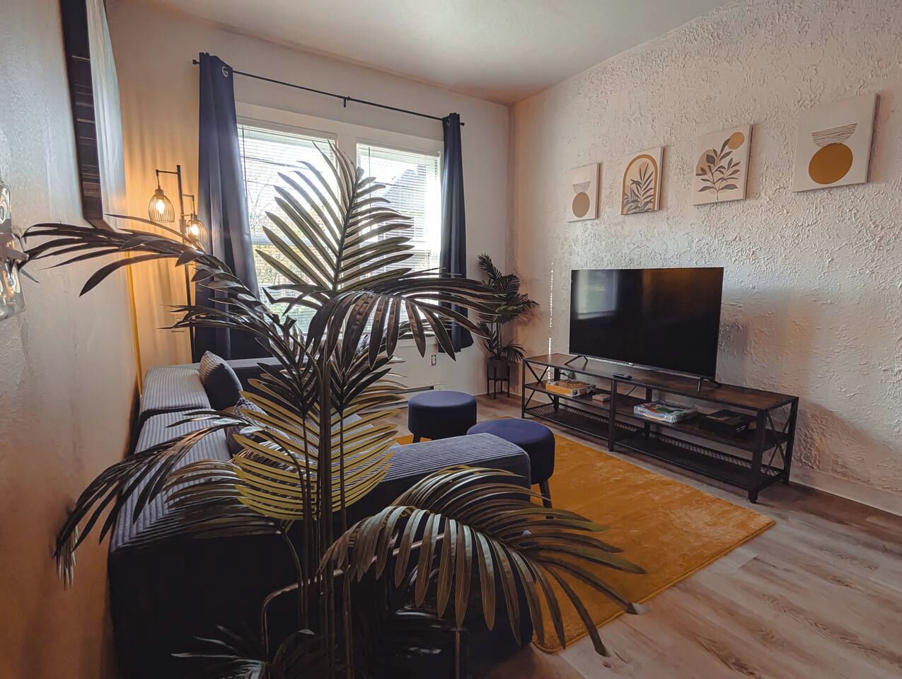 A modern living room with a large flat-screen TV, a sofa, a coffee table, and a potted plant.