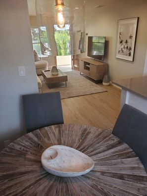 Ein modernes Wohnzimmer mit einer zentralen Wendeltreppe, einem Fernseher und einem großen Fenster mit Blick auf Grünflächen.