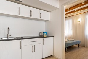 Een moderne keuken met witte kasten en een zwart aanrecht, een spoelbak en een waterkoker.
