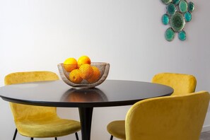 A round table with a woven fruit bowl containing oranges, surrounded by yellow chairs. - Magherita Home Venice apartment (Venice)