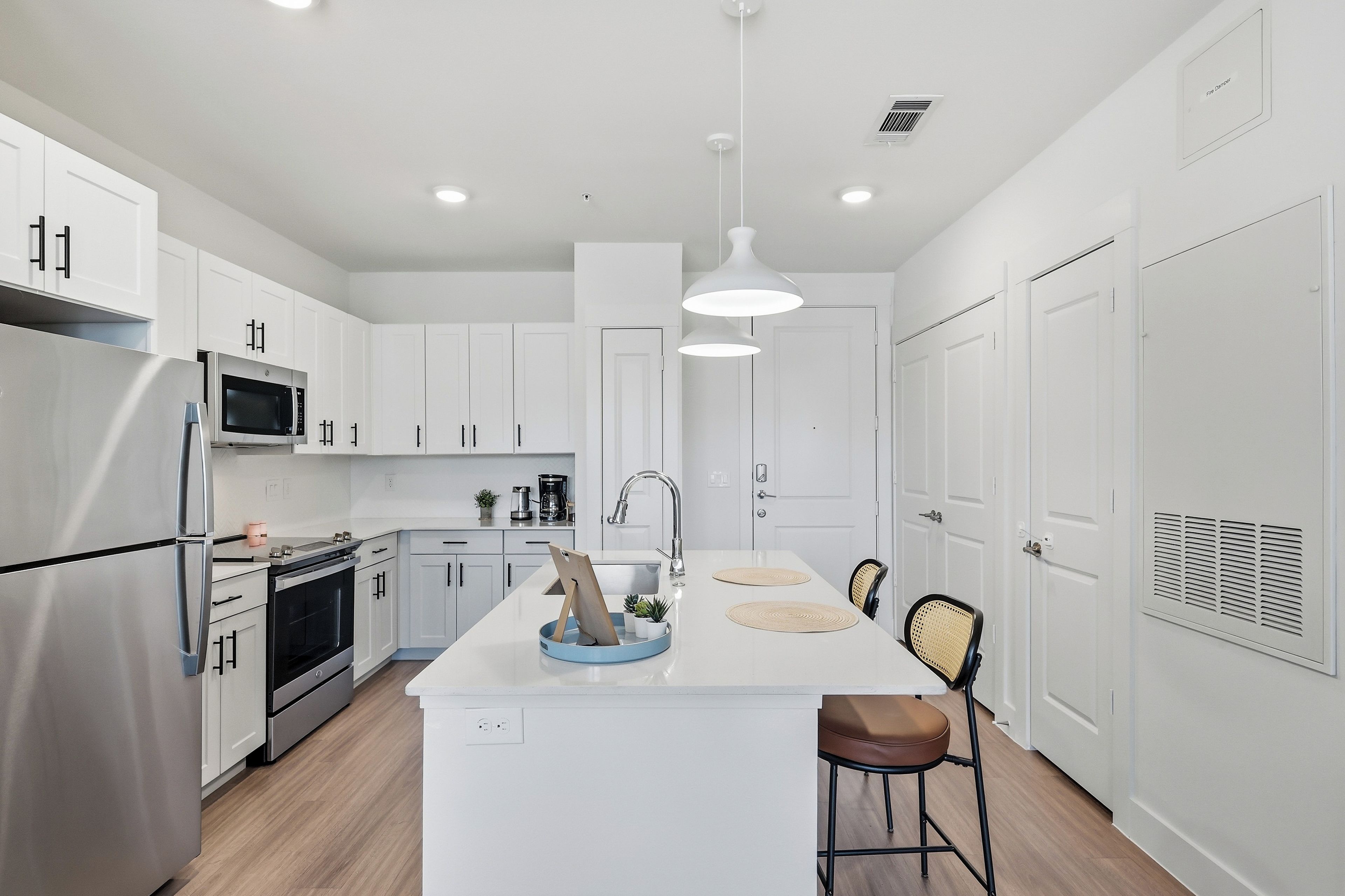 Una cocina moderna con armarios blancos, electrodomésticos de acero inoxidable y una isla central con asientos.