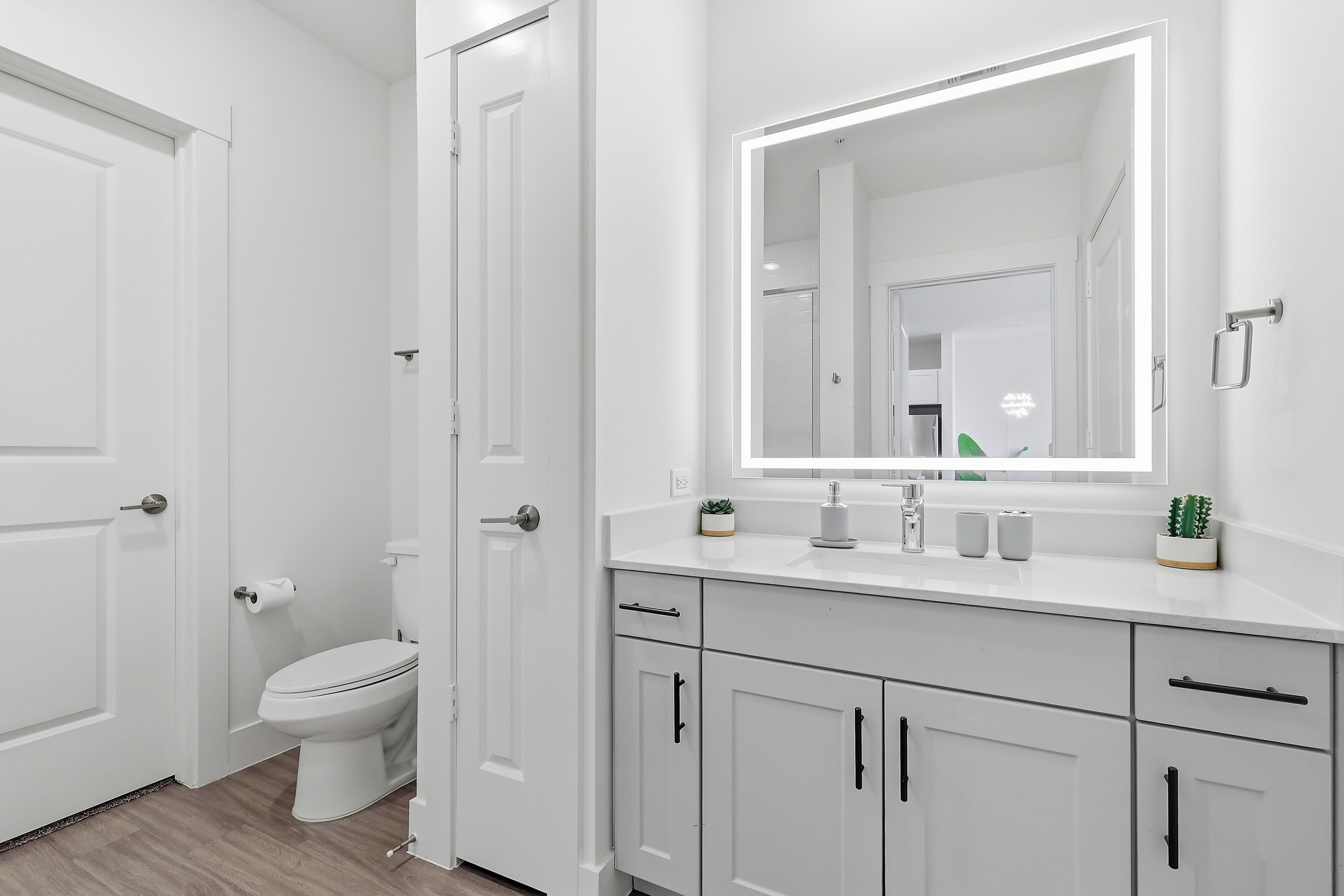 Ein modernes Badezimmer mit Toilette, Waschbecken, Spiegel und Schränken.