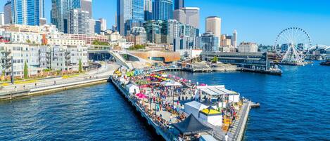 A waterfront pier with a crowd, a Ferris wheel, and modern city buildings in the background.