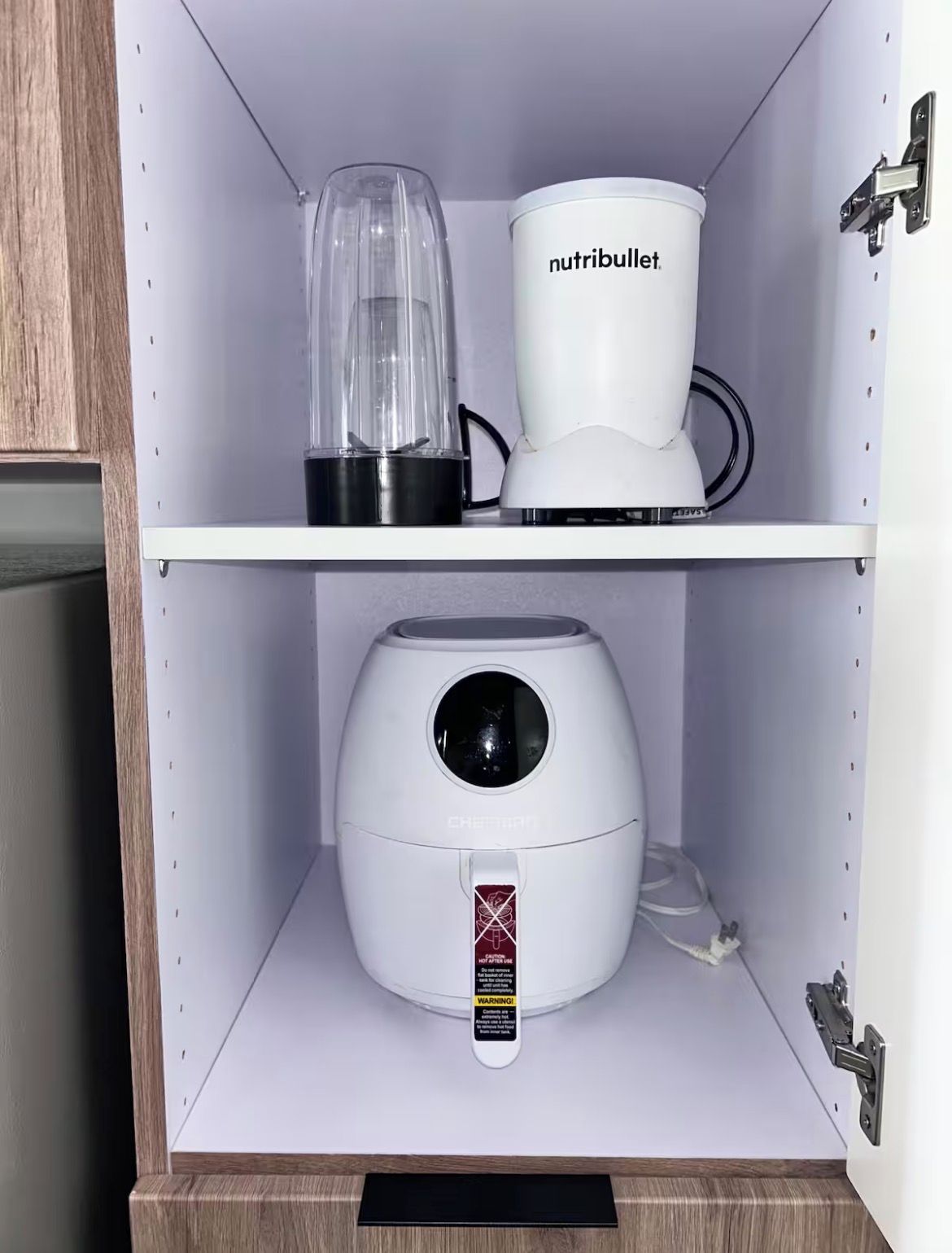 Um armário de cozinha com um liquidificador, cafeteira e fritadeira elétrica.