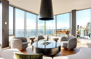 A modern living room with large windows, a round coffee table, and grey upholstered chairs.