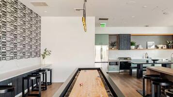 A modern kitchen with a central island, bar stools, and a wall of framed photos.