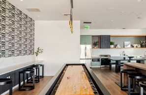 Una cocina moderna con una isla central, taburetes de bar y una pared de fotografías enmarcadas.