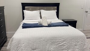 A bedroom with a bed, a dresser, and a nightstand.