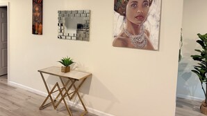 A gallery with artwork on the walls, a small table with a plant, and a potted plant to the side.