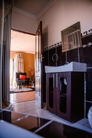 Ein Hotelzimmer mit einem Badezimmer, das ein Waschbecken, einen Spiegel und einen Duschbereich beinhaltet.
