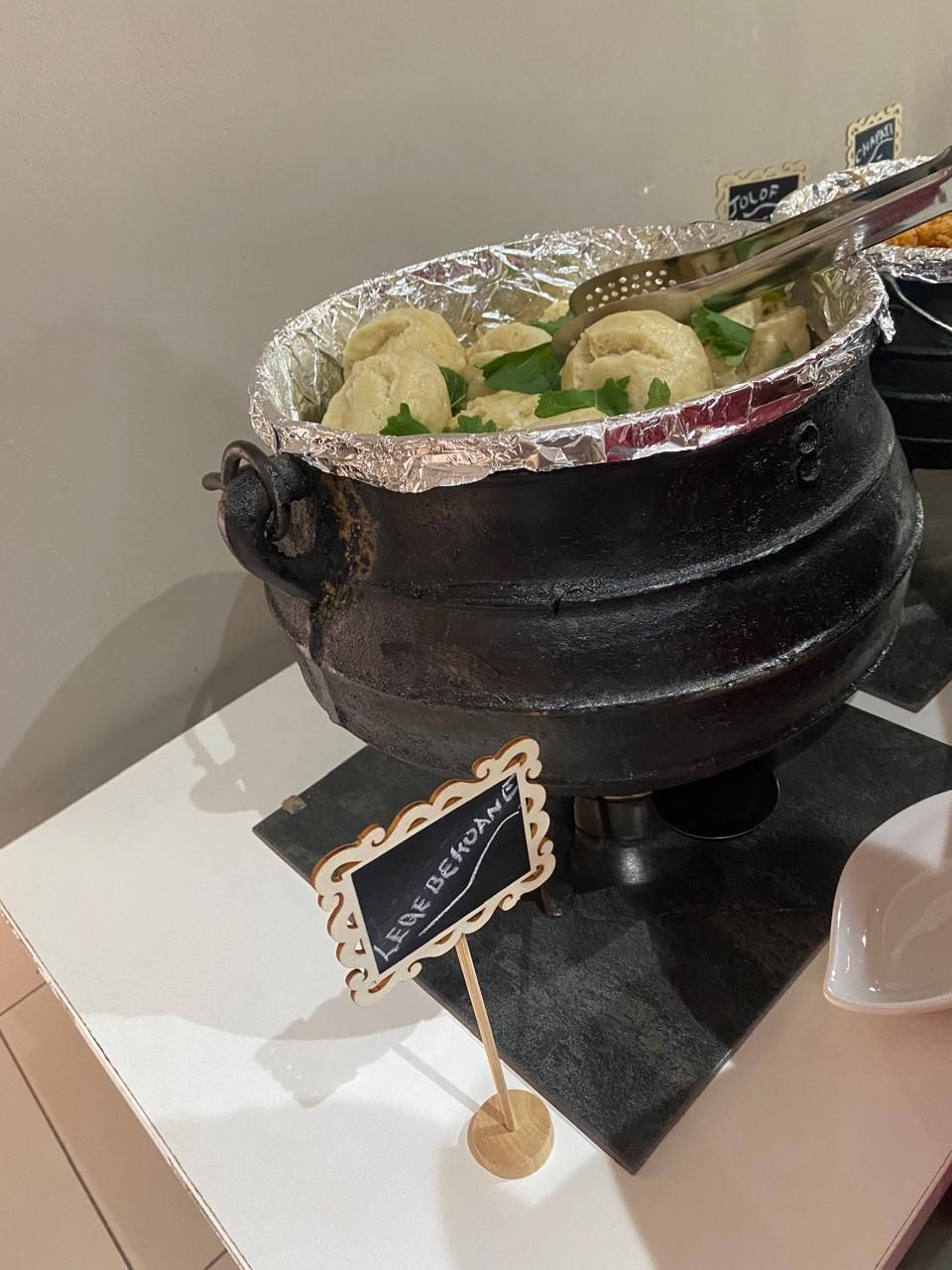 A black pot with foil on top, labeled 'JULO'S BEEF,' on a black countertop.