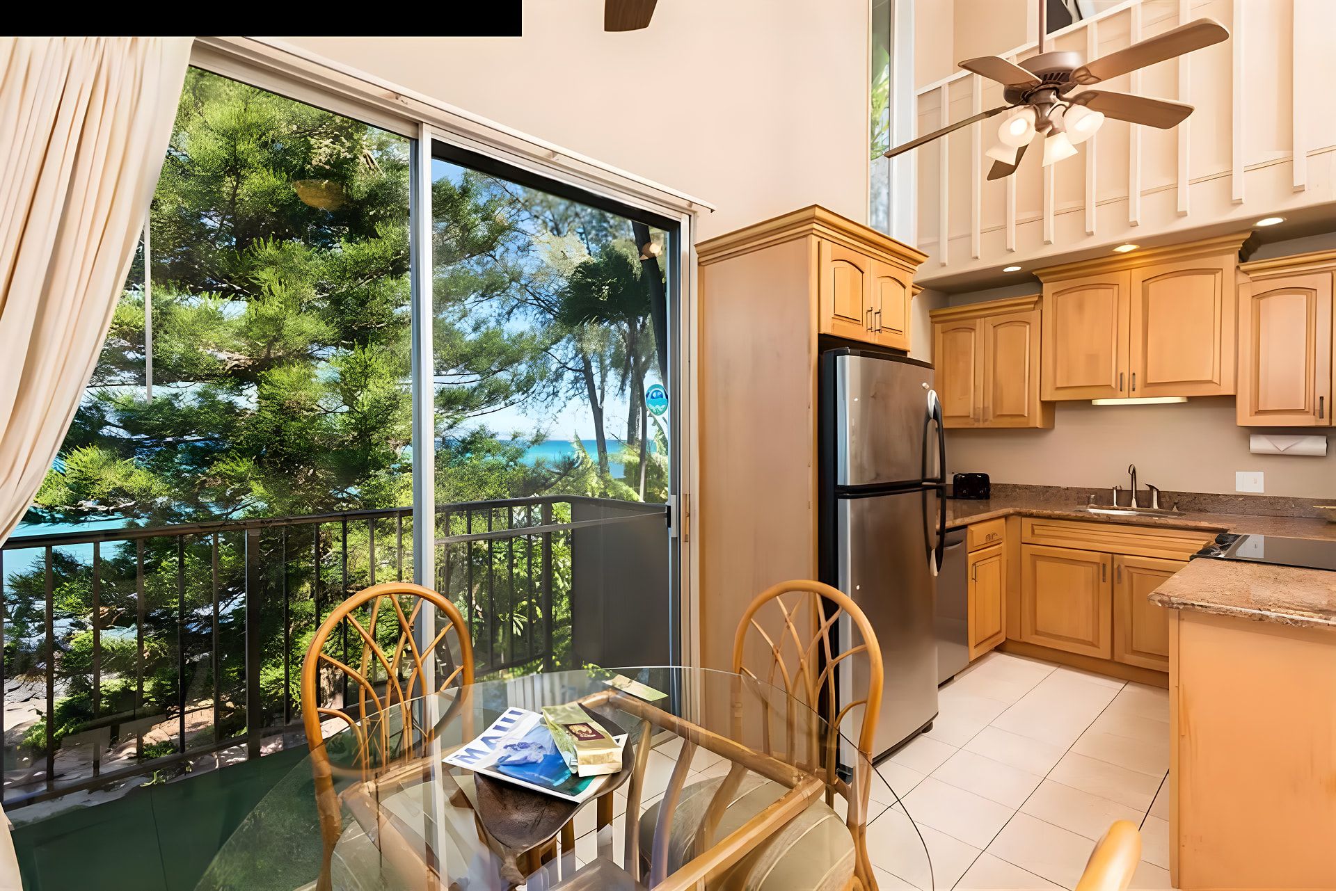 A kitchen with a refrigerator, wooden cabinets, and a dining area with a glass table and chairs.