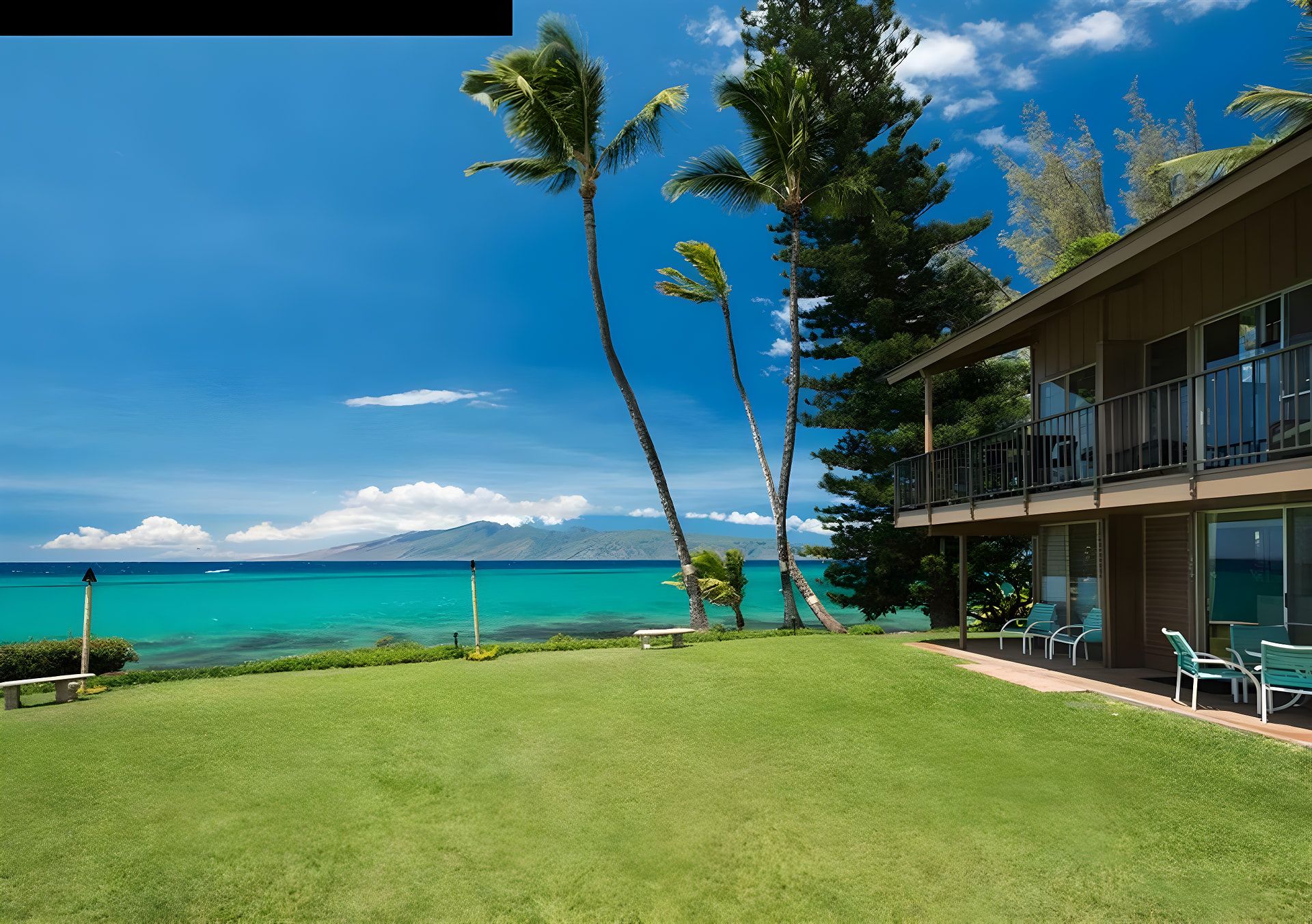 A hotel with a view of a turquoise sea and a mountain in the distance.