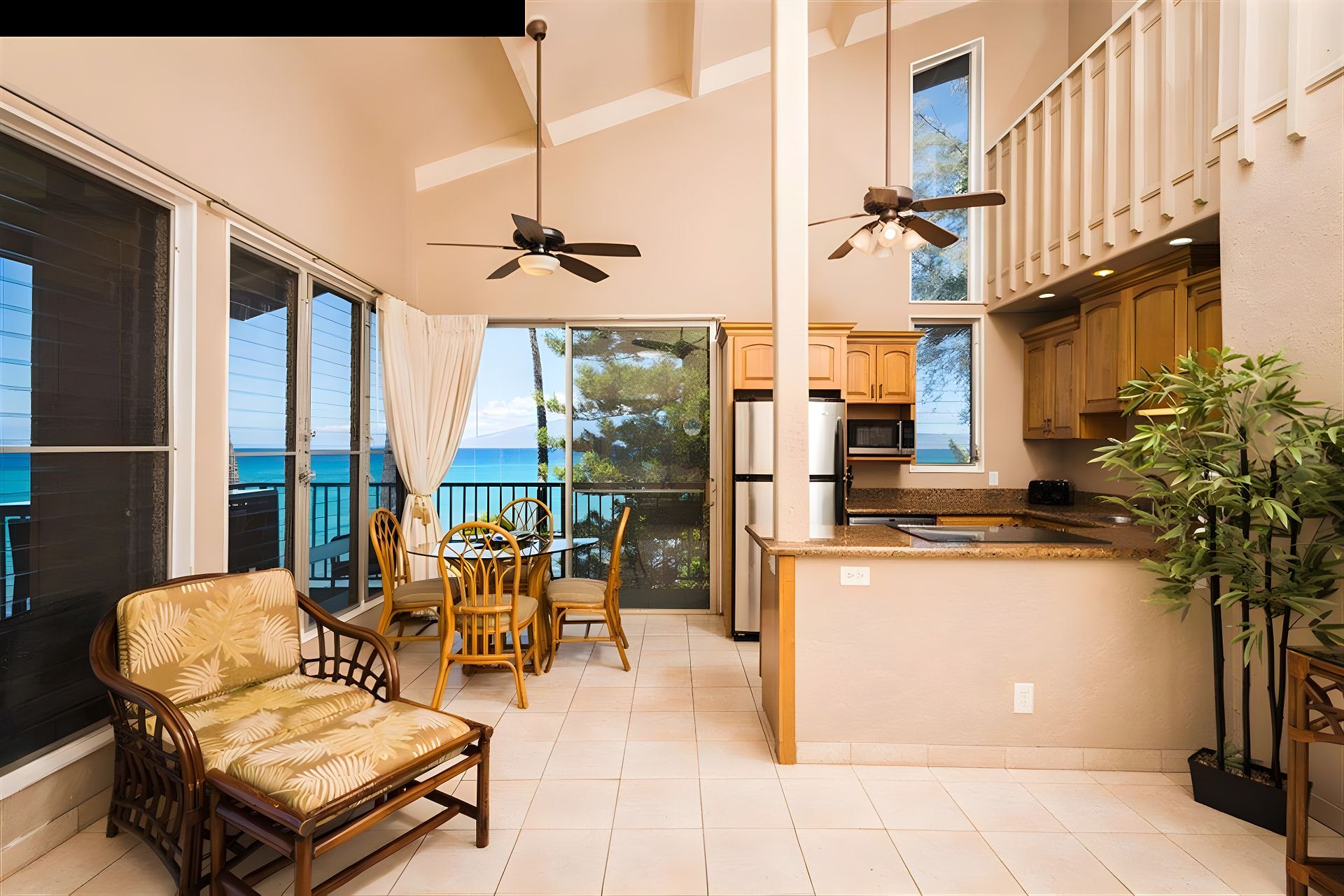 Ein geräumiger Balkon mit Essbereich, Deckenventilatoren und Blick aufs Meer.