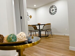 A dining area with a table, chairs, and a wall clock.