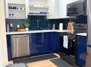 A modern kitchen with stainless steel appliances, blue cabinets, and a white countertop. - Beautiful suite close to Spruce Meadows in Calgary, Canada (Calgary)