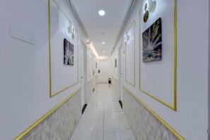 A corridor with white walls, gold trim, and artwork. - Classic Suvedhi Tower (Kunnathunad)