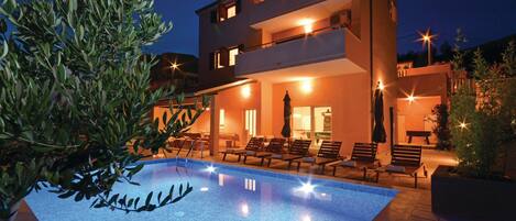 A modern two-story building with a swimming pool and outdoor seating area.