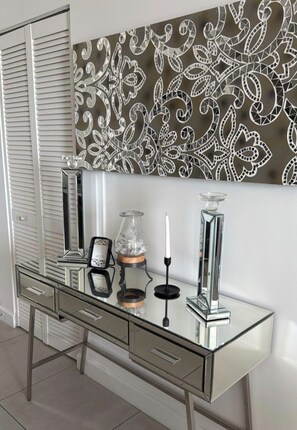 A modern bathroom vanity with a glass top, a mirror, and a decorative wall piece. - Modern 1-bedroom apartment with AC in serene Doral (Doral)