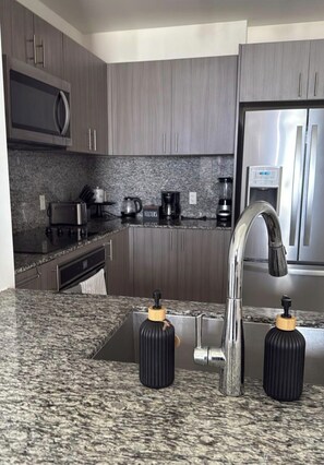 A modern kitchen with granite countertops, stainless steel appliances, and a built-in oven. - Modern 1-bedroom apartment with AC in serene Doral (Doral)