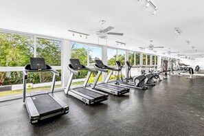 A gym with treadmills, exercise bikes, and weight machines, large windows with a view of trees, and ceiling fans. - ~Sunny ~Apartment • Relax Steps from the Sand (Nuevo Nayarit)
