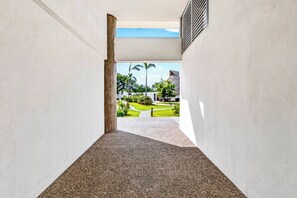 A corridor with a concrete floor leading to a grassy area with a building in the background. - ~Sunny ~Apartment • Relax Steps from the Sand (Nuevo Nayarit)