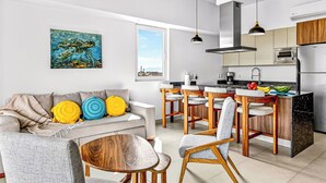 Et moderne køkken med spiseplads, en sofa med farverige puder og et maleri på væggen.