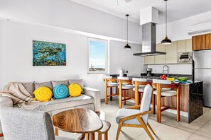 Eine moderne Küche mit Essbereich, einem Sofa mit bunten Kissen und einem Gemälde an der Wand.