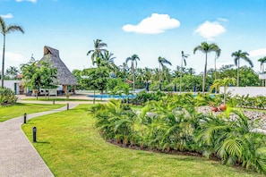 Ein Resort mit einem strohgedeckten Gebäude, einem Swimmingpool und tropischer Bepflanzung.